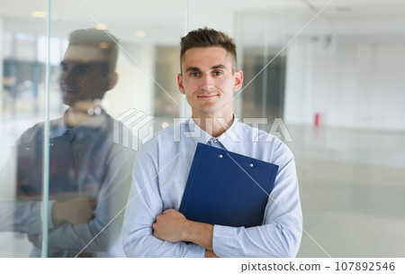 Handsome man in shirt and folder stand Handsome man in shirt and folder stand 107892546