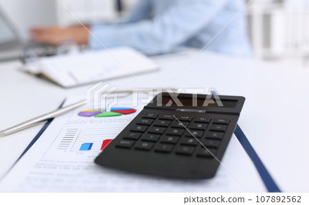 The black calculator lies on a chessboard 107892562