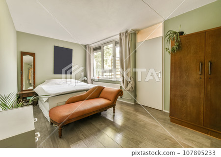 a bedroom with a bed and an orange chair in front of the door that leads to another room on the other side a bedroom with a bed and an orange chair in front of the door that leads to another room on the other side 107895233