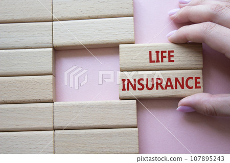 Life insurance symbol. Concept word Life insurance on wooden blocks. Businessman hand. Beautiful pink background. Business and Life insurance concept. Copy space Life insurance symbol. Concept word Life insurance on wooden blocks. Businessman hand. Beautiful pink background. Business and Life insurance concept. Copy space 107895243
