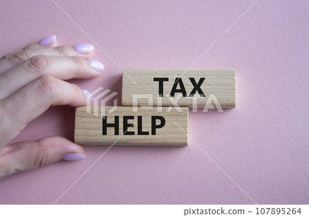Tax Help symbol. Concept word Tax Help on wooden blocks. Businessman hand. Beautiful pink background. Business and Tax Help concept. Copy space Tax Help symbol. Concept word Tax Help on wooden blocks. Businessman hand. Beautiful pink background. Business and Tax Help concept. Copy space 107895264
