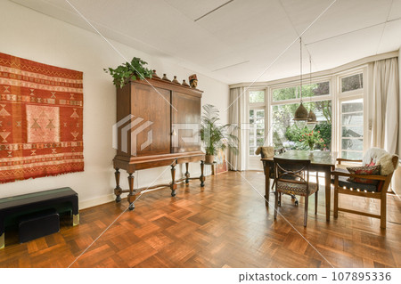 a living room with wood flooring and an oriental rug hanging on the wall in the room is decorated with plants a living room with wood flooring and an oriental rug hanging on the wall in the room is decorated with plants 107895336