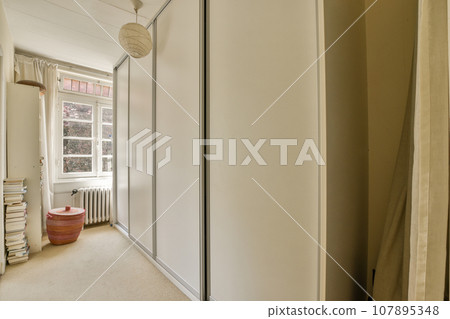 a room with white walls and beige carpeting, including a large mirror on the wall next to the closet door a room with white walls and beige carpeting, including a large mirror on the wall next to the closet door 107895348