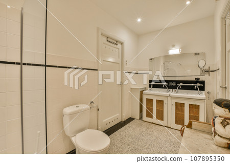a white bathroom with black and white tiles on the floor, sink, toilet, mirror and shower stall door a white bathroom with black and white tiles on the floor, sink, toilet, mirror and shower stall door 107895350