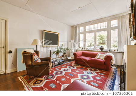 a living room with two chairs and a red rug on the floor in front of the couch is next to the fireplace 107895361