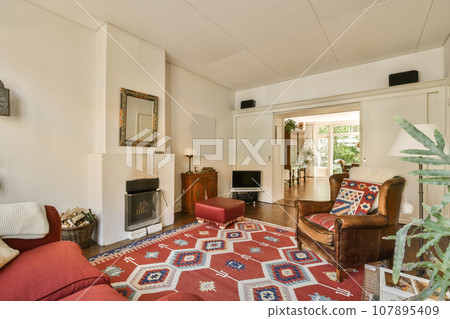 a living room with red couches and an area rug on the floor in front of the sofa is a fire place 107895409