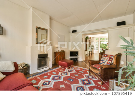a living room with red couches and an area rug on the floor in front of the sofa is a fire place 107895419