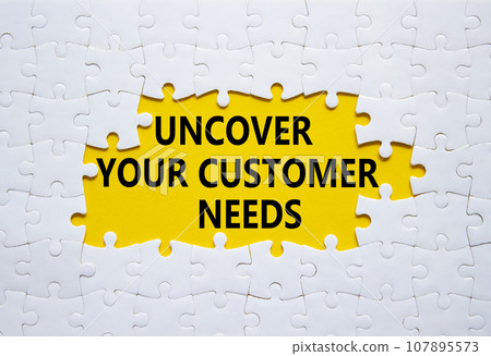 Customer Needs symbol. White puzzle with words Uncover your Customer Needs. Beautiful yellow background. Business concept. Copy space. 107895573