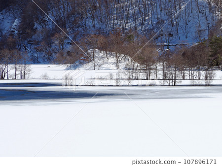 Lake Akimoto in Fukushima Prefecture is mostly frozen. The lake's surface is beautiful with its gradation between the blue surface of the lake and the white snowy field, and the accents of the standing trees. Lake Akimoto in Fukushima Prefecture is mostly frozen. The lake's surface is beautiful with its gradation between the blue surface of the lake and the white snowy field, and the accents of the standing trees. 107896171