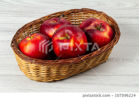 Red apples in a wicker basket on the wooden table. Red apples in a wicker basket on the wooden table. 107896224