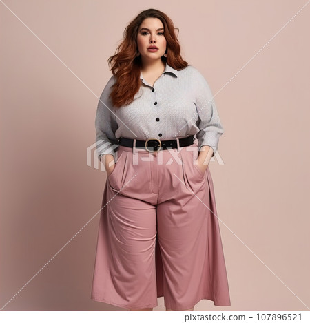 Beautiful young lady plus size model posing on solid color studio background, elegant dressed curvy woman 107896521