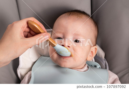 A little boy caucasian has been trying porridge and fruit puree for 6 months. Weight gain in infants, caloric content of food, close-up A little boy caucasian has been trying porridge and fruit puree for 6 months. Weight gain in infants, caloric content of food, close-up 107897092