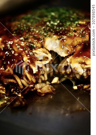 Okonomiyaki with sauce grilled on an iron plate Okonomiyaki with sauce grilled on an iron plate 107898545