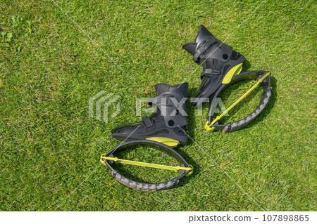 Kangoo jumps bots on green grass. Black Kangoo sneakers. Shoes for fitness. Top view 107898865