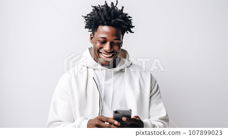 A modern cheerful dark-skinned guy is typing text message on mobile phone, enjoying online communication A modern cheerful dark-skinned guy is typing text message on mobile phone, enjoying online communication 107899023