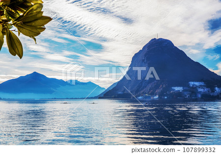 Awe panorama of  Lugano lake,  Swiss Alps and kayaks moves in water 107899332