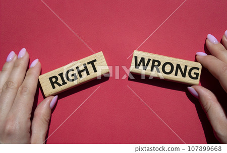 Right or Wrong symbol. Concept word Right or Wrong on wooden blocks. Businessman hand. Beautiful red background. Business and Right or Wrong concept. Copy space 107899668