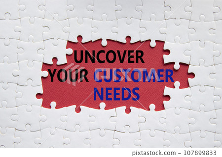 Customer Needs symbol. White puzzle with words Uncover your Customer Needs. Beautiful red background. Business concept. Copy space. 107899833