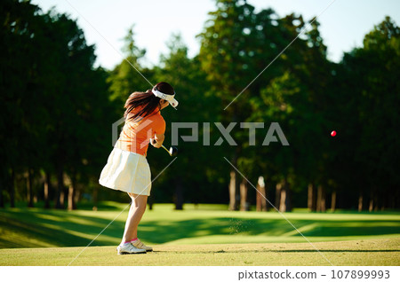 一位 40 多歲的女性正在打高爾夫球 107899993
