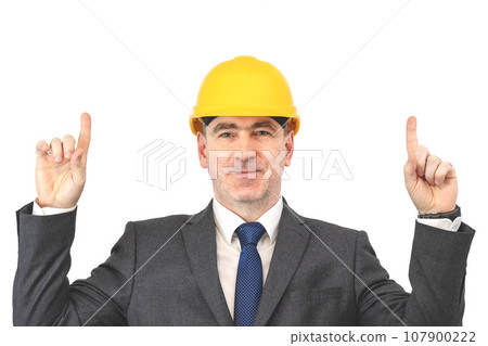 A man in a helmet shows his hands up. A builder man in a suit points up with his fingers 107900222