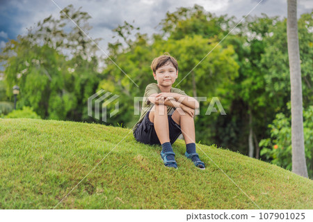 Young boy sitting in the grass on a sunny day 107901025