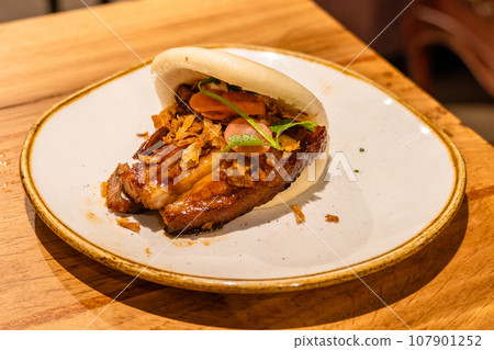 Low temperature roasted bacon bao with crispy onion and coriander Low temperature roasted bacon bao with crispy onion and coriander 107901252