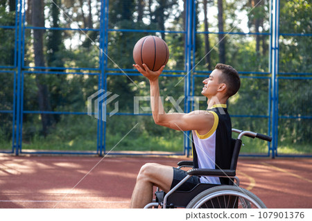 Man with a disability in wheelchair at a park, has workout and weekend fun or active basketball match. 107901376