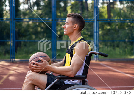 Basketball player man in wheelchair has disability playing on court, holding ball. 107901380