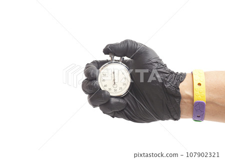 doctor's hand in black surgical medical gloves holds an activated mechanical stopwatch. doctor's hand in black surgical medical gloves holds an activated mechanical stopwatch. 107902321