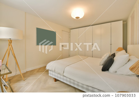 a bedroom with white walls and wood flooring, including a large bed in the room has a tv mounted on the wall 107903033