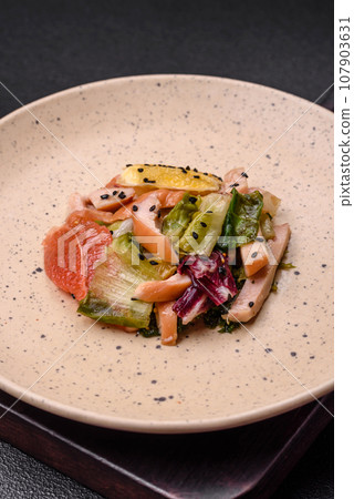 Delicious fresh juicy salad of sliced chicken, grapefruit, lettuce, sesame with olive oil 107903631