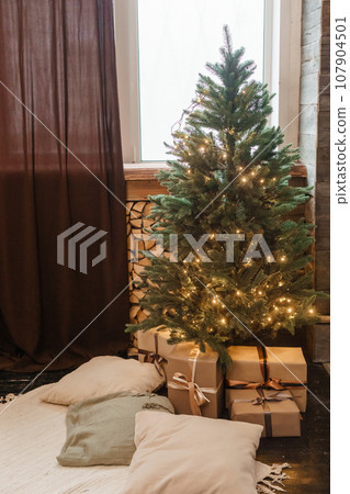 Designer Christmas tree decoration with lights. The concept of celebrating New Year and Christmas. Gifts in craft packaging under the Christmas tree. Designer Christmas tree decoration with lights. The concept of celebrating New Year and Christmas. Gifts in craft packaging under the Christmas tree. 107904501