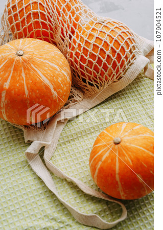 Mesh shopping bag with vegetables. Autumn pumpkin harvest Mesh shopping bag with vegetables. Autumn pumpkin harvest 107904521