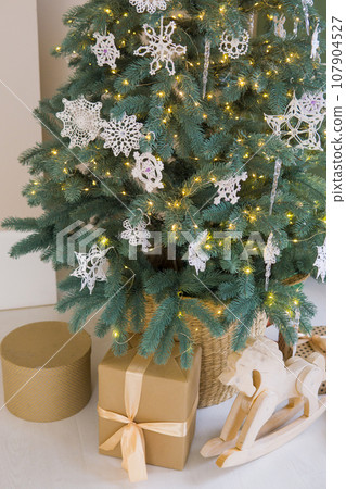 The interior of a children's room decorated for the Christmas holidays. A Christmas tree with garlands and a children's wardrobe with soft pillows. 107904527