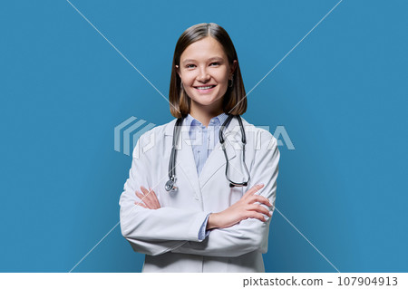 Portrait of young woman doctor student intern in white coat on blue background Portrait of young woman doctor student intern in white coat on blue background 107904913