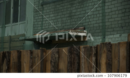 A ruined building under reconstruction behind the wooden fence. Clip. An empty apartment building, house is in a non residential condition. A ruined building under reconstruction behind the wooden fence. Clip. An empty apartment building, house is in a non residential condition. 107906179