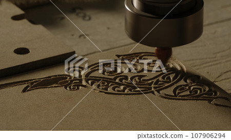 Carving geometric pattern on wooden sheet with small drill at woodwork factory, macro view. Creative. Wood lathe machine processes detail creating sawdust. Carving geometric pattern on wooden sheet with small drill at woodwork factory, macro view. Creative. Wood lathe machine processes detail creating sawdust. 107906294