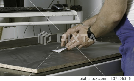 Carpenter putting paper sticker on a wooden board. Creative. A man works with a tree, woodworking and traditional carpentry. Carpenter putting paper sticker on a wooden board. Creative. A man works with a tree, woodworking and traditional carpentry. 107906366