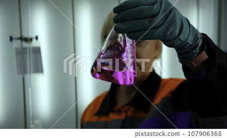 Chemist holds flask with pink liquid, shakes it and fluid substance changes color. Clip. Pink mixture becoming transparent. Chemist holds flask with pink liquid, shakes it and fluid substance changes color. Clip. Pink mixture becoming transparent. 107906368