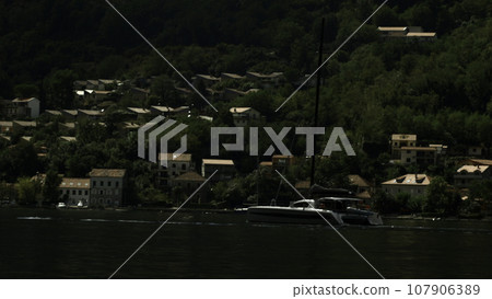 Sailing yacht moored by the lake coast in Italy. Creative. Romantic atmosphere. Calm and pacifying scene with a sailboat. Sailing yacht moored by the lake coast in Italy. Creative. Romantic atmosphere. Calm and pacifying scene with a sailboat. 107906389