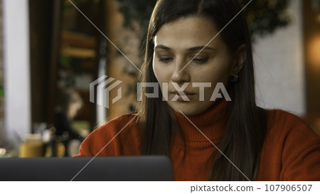 Beautiful woman is typing on laptop in cafe. Stock footage. Attractive young woman is working at laptop in cafe. Beautiful woman is typing on laptop while freelancing in cafe Beautiful woman is typing on laptop in cafe. Stock footage. Attractive young woman is working at laptop in cafe. Beautiful woman is typing on laptop while freelancing in cafe 107906507
