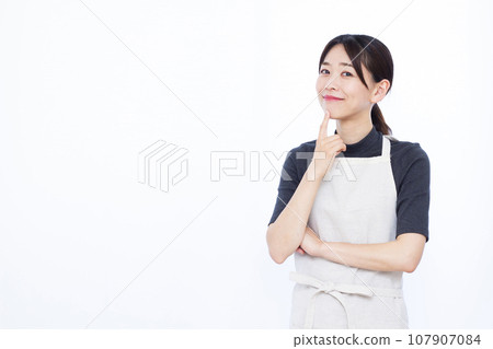 A housewife in her 30s smiling and thinking in front of a white background 107907084