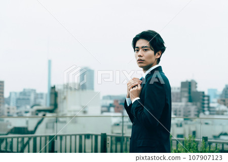 Young businessman adjusting his tie in the city Young businessman adjusting his tie in the city 107907123