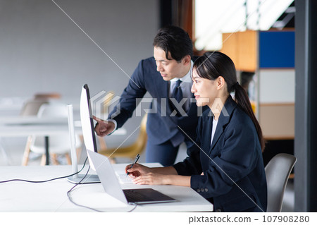 Business person talking while looking at a computer Business person talking while looking at a computer 107908280