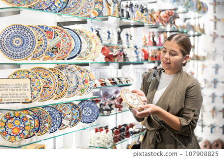 Portrait of happy woman near souvenirs shelves in store Portrait of happy woman near souvenirs shelves in store 107908825