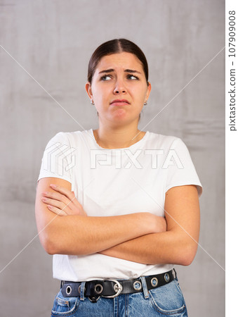 Sad young woman posing crossly against gray background Sad young woman posing crossly against gray background 107909008