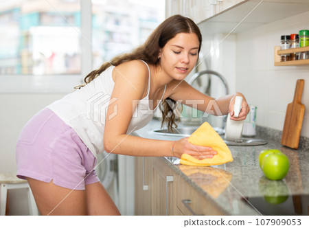 Young positive woman doing chores cleaning kitchen 107909053