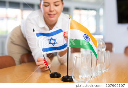 Unrecognizable girl sets midget flags of India and Israel before international negotiations 107909107