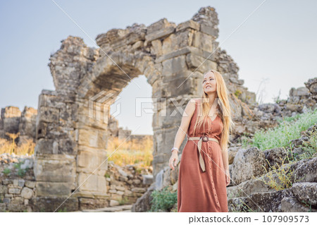 Woman tourist explores Aspendos Ancient City. Aspendos acropolis city ruins, cisterns, aqueducts and old temple. Aspendos Antalya Turkey. turkiye 107909573