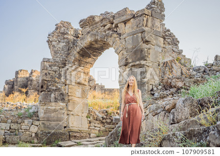 Woman tourist explores Aspendos Ancient City. Aspendos acropolis city ruins, cisterns, aqueducts and old temple. Aspendos Antalya Turkey. turkiye 107909581